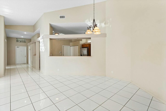 tiled spare room with vaulted ceiling and an inviting chandelier