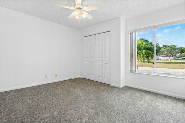 unfurnished bedroom featuring carpet flooring, a textured ceiling, a closet, and ceiling fan