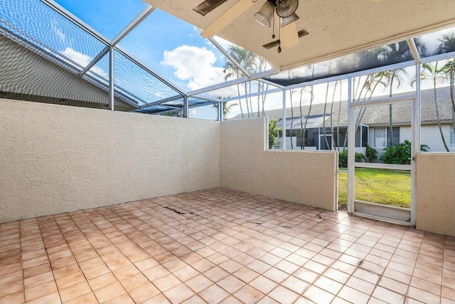 unfurnished sunroom featuring beam ceiling, ceiling fan, and plenty of natural light