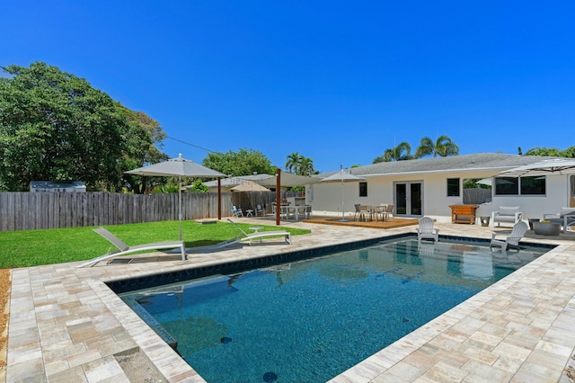 view of pool with a yard, a patio, and french doors