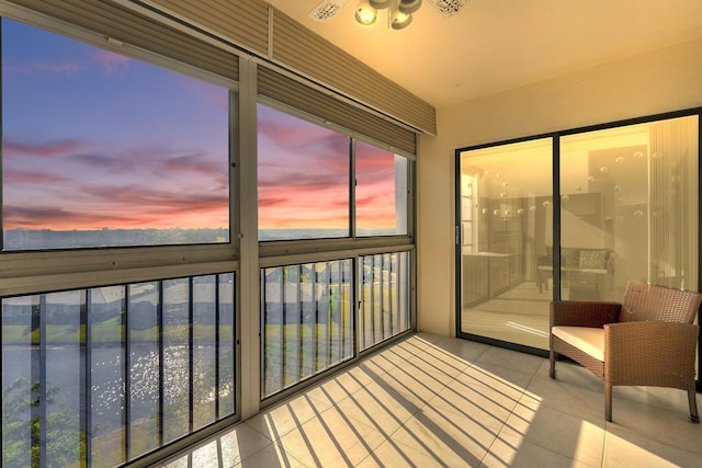 balcony at dusk featuring a water view