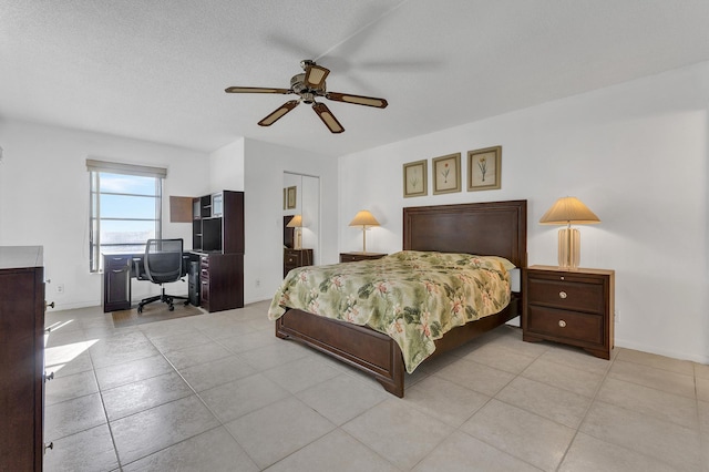 bedroom featuring ceiling fan, light tile patterned floors, and a textured ceiling