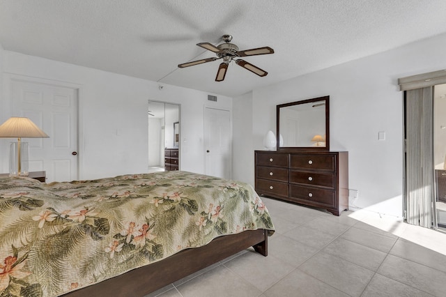 bedroom with a textured ceiling, ceiling fan, and light tile patterned flooring