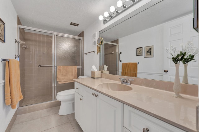 bathroom featuring tile patterned flooring, vanity, a shower with shower door, and a textured ceiling