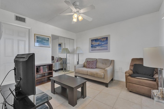 tiled living room with ceiling fan and a textured ceiling