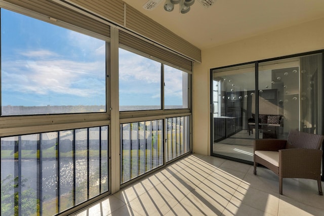 sunroom featuring ceiling fan and a water view