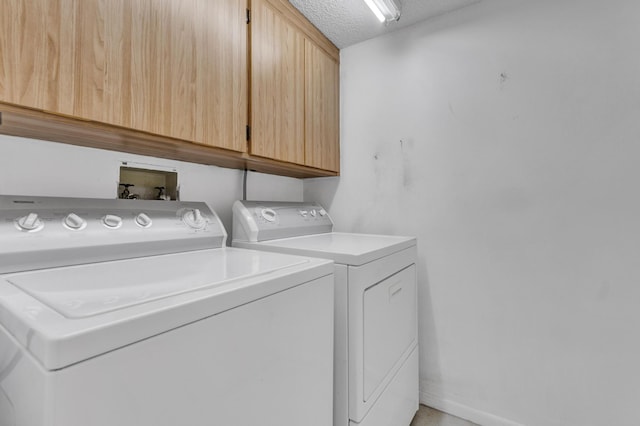 laundry room with cabinets, a textured ceiling, and separate washer and dryer