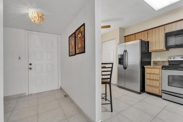 kitchen featuring light tile patterned flooring, a textured ceiling, and appliances with stainless steel finishes