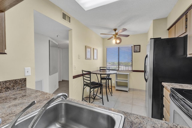 kitchen with stainless steel range with electric stovetop, a textured ceiling, ceiling fan, sink, and light tile patterned floors