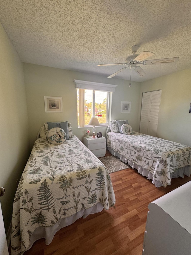 bedroom with ceiling fan, a closet, wood-type flooring, and a textured ceiling