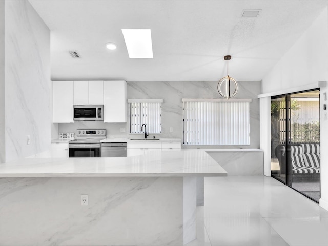 kitchen with white cabinets, sink, hanging light fixtures, appliances with stainless steel finishes, and kitchen peninsula