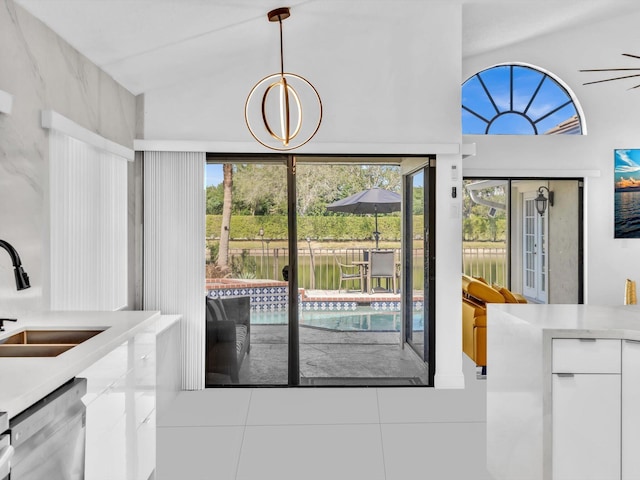 dining space with a healthy amount of sunlight, tile patterned floors, lofted ceiling, and sink