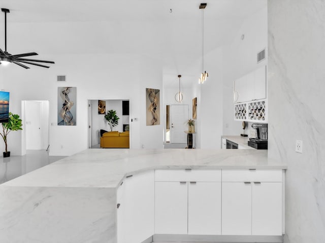 kitchen with white cabinetry, ceiling fan, hanging light fixtures, light stone counters, and kitchen peninsula