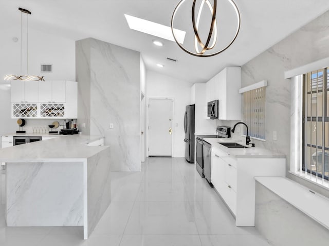 kitchen featuring decorative light fixtures, stainless steel appliances, a wealth of natural light, and vaulted ceiling with skylight