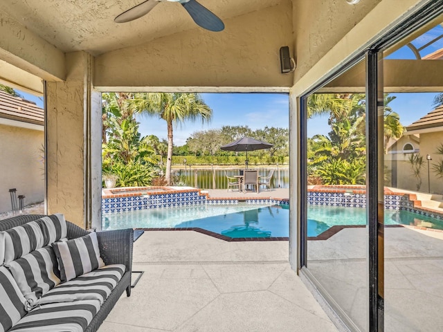 view of pool with a patio area, an in ground hot tub, a water view, and ceiling fan