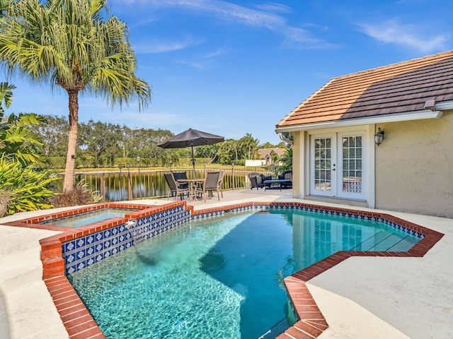 view of pool with a patio area, an in ground hot tub, french doors, and a water view