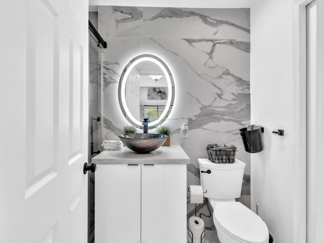 bathroom with vanity, toilet, and tile walls