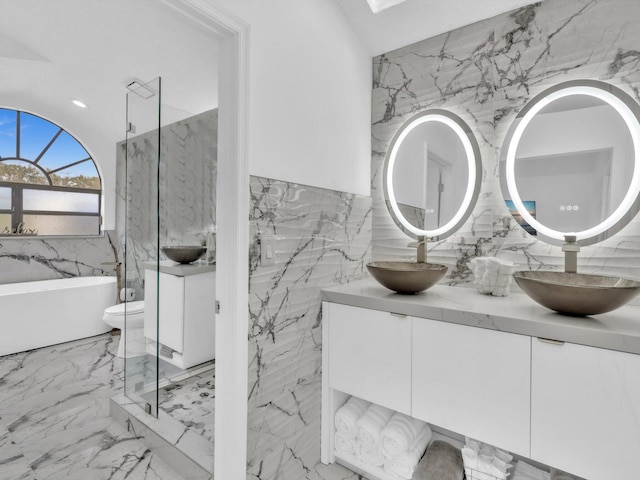 bathroom with vanity, toilet, tile walls, and a washtub