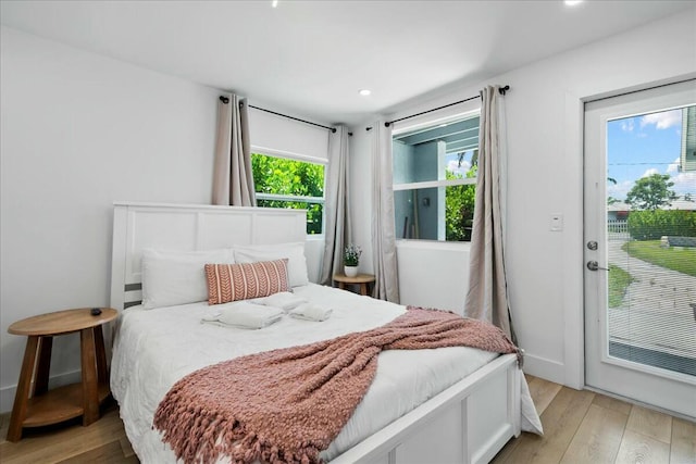 bedroom with access to outside, multiple windows, and light hardwood / wood-style floors