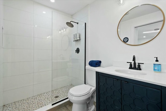 bathroom with a tile shower, vanity, and toilet