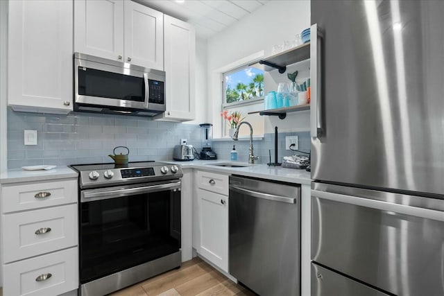 kitchen featuring white cabinetry, sink, tasteful backsplash, light hardwood / wood-style floors, and appliances with stainless steel finishes