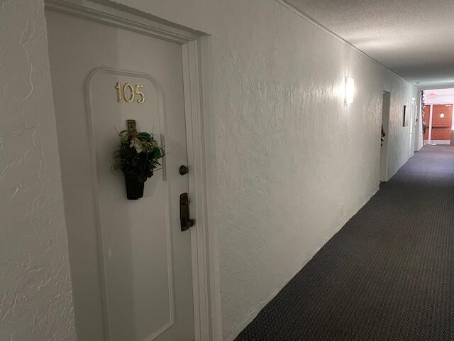 hall with carpet and a textured ceiling