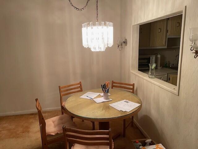 carpeted dining room featuring a notable chandelier and sink