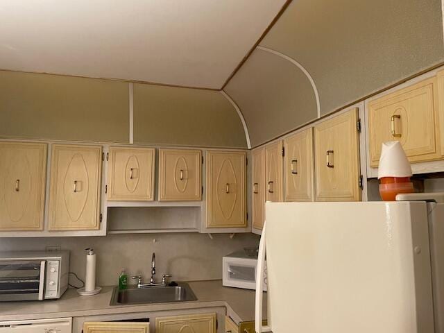 kitchen featuring light brown cabinetry, white appliances, and sink