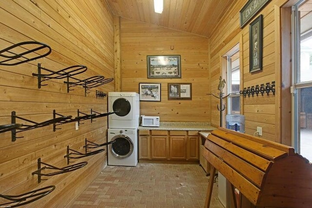 washroom featuring cabinets, stacked washer and dryer, wooden walls, and wood ceiling