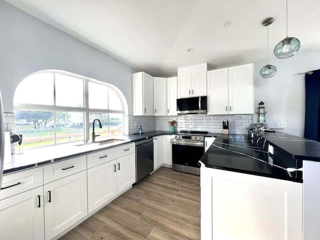 kitchen featuring decorative light fixtures, white cabinetry, sink, and appliances with stainless steel finishes