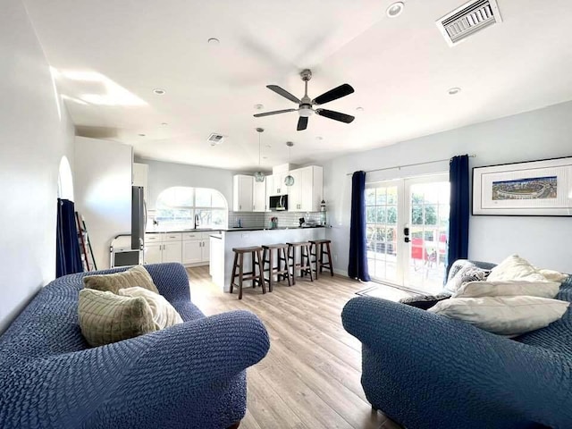 living room with ceiling fan, french doors, light hardwood / wood-style floors, and sink