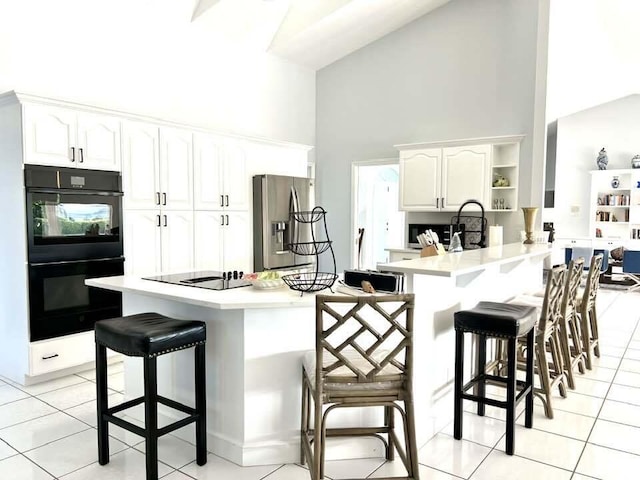 kitchen with a kitchen breakfast bar, high vaulted ceiling, kitchen peninsula, white cabinets, and black appliances