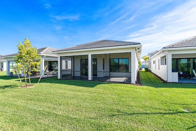 rear view of property featuring a lawn and a sunroom