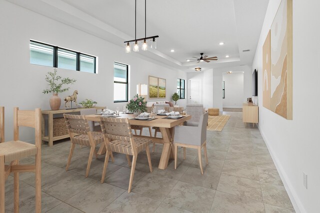 tiled dining space featuring ceiling fan and a tray ceiling