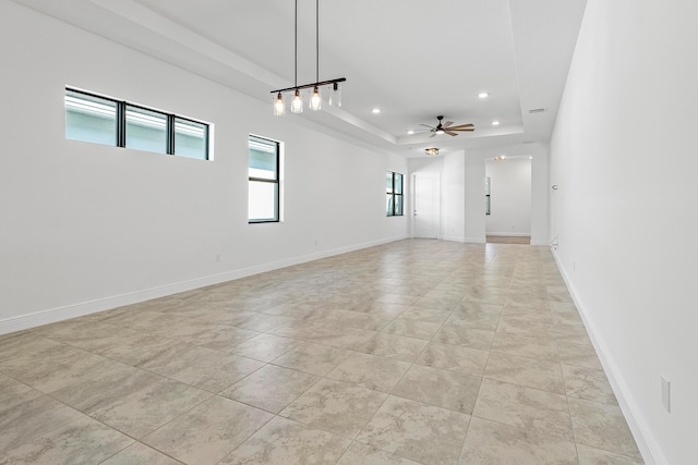 unfurnished room featuring ceiling fan and a raised ceiling