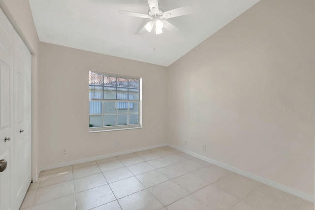 spare room featuring ceiling fan, light tile patterned floors, and vaulted ceiling