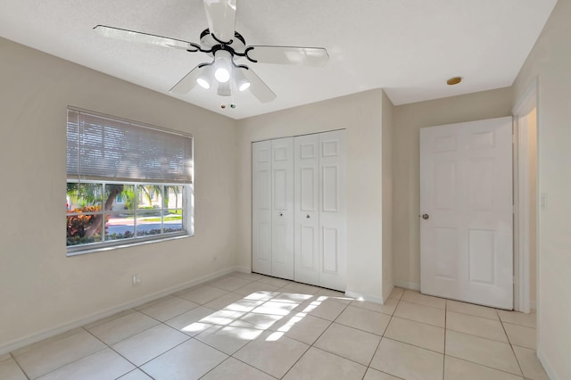 unfurnished bedroom featuring ceiling fan, light tile patterned floors, and a closet