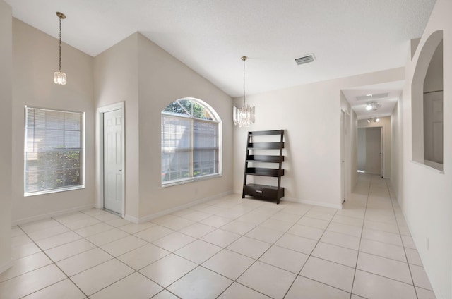 unfurnished dining area with light tile patterned flooring, a towering ceiling, and an inviting chandelier