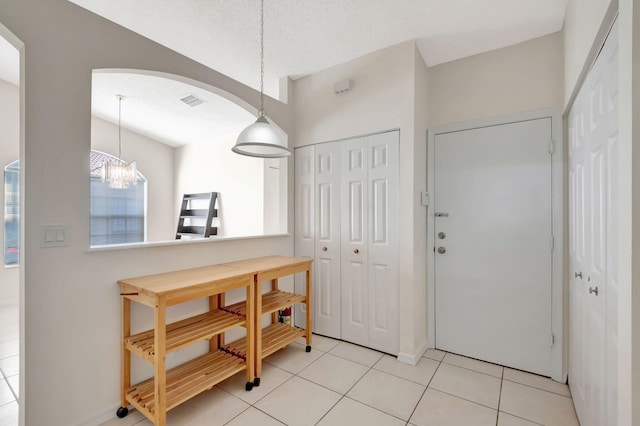 entrance foyer featuring light tile patterned floors, a textured ceiling, and a chandelier