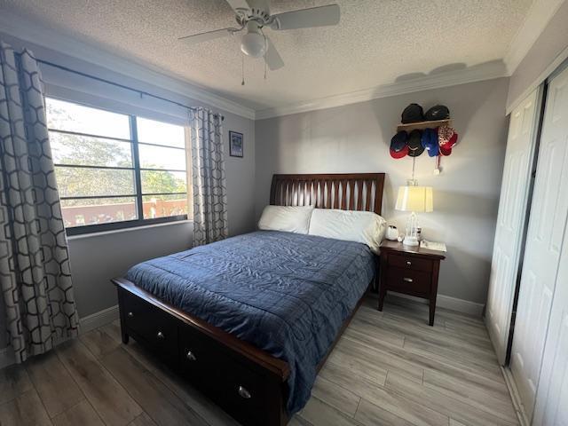 bedroom featuring hardwood / wood-style flooring, ceiling fan, ornamental molding, and a closet