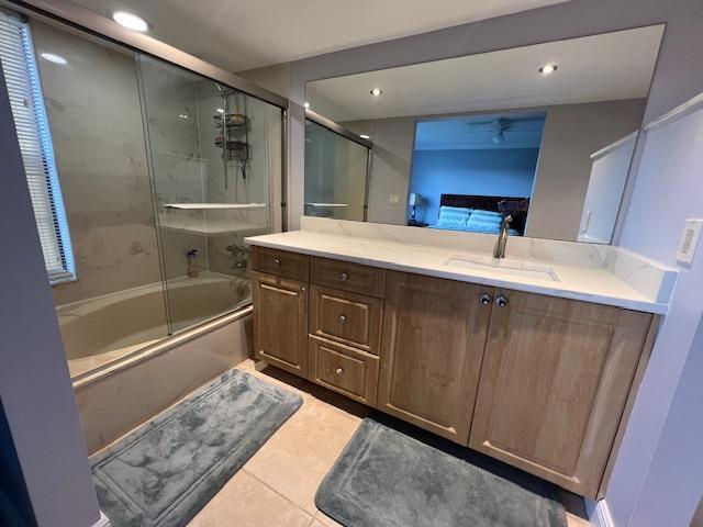 bathroom featuring tile patterned flooring, vanity, and bath / shower combo with glass door