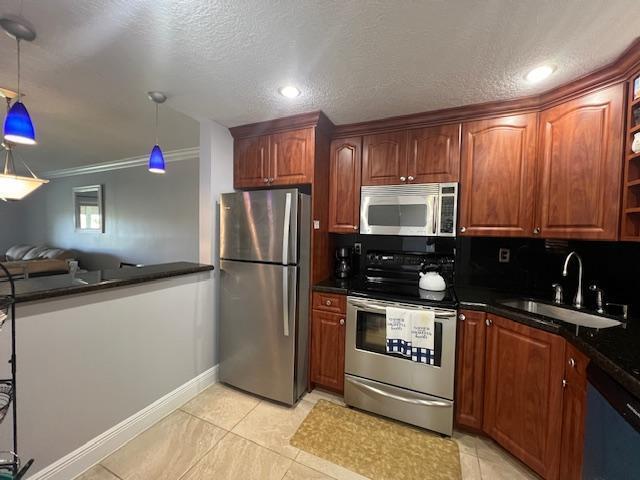 kitchen featuring sink, stainless steel appliances, pendant lighting, a textured ceiling, and ornamental molding