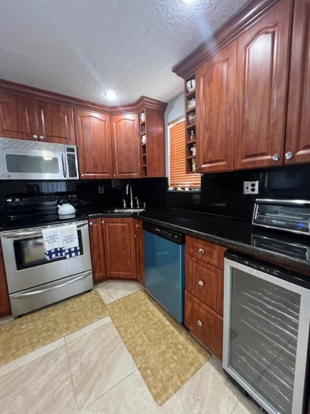 kitchen with backsplash, sink, beverage cooler, and appliances with stainless steel finishes