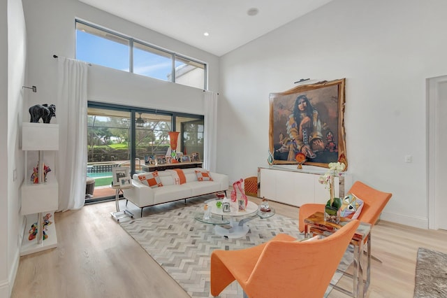 living room with light hardwood / wood-style floors, high vaulted ceiling, and a healthy amount of sunlight