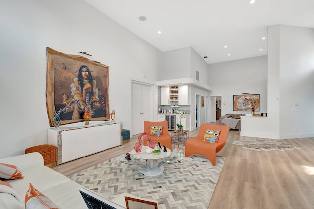 living room with beverage cooler, light hardwood / wood-style floors, and a high ceiling