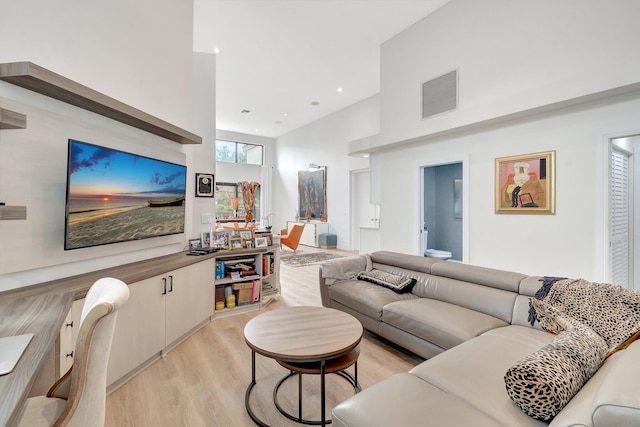 living room featuring light wood-type flooring and a towering ceiling