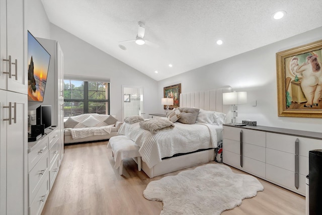 bedroom with a textured ceiling, light wood-type flooring, vaulted ceiling, and ceiling fan