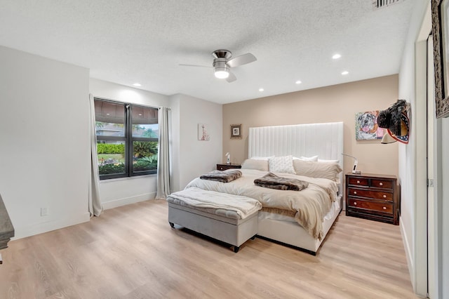 bedroom featuring ceiling fan, light hardwood / wood-style floors, and a textured ceiling