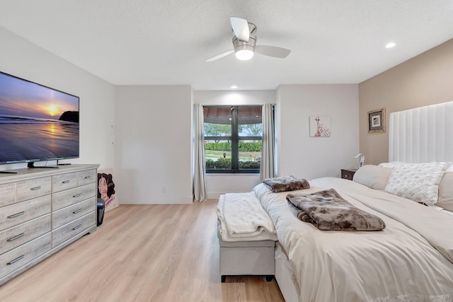 bedroom featuring ceiling fan, light hardwood / wood-style flooring, and a textured ceiling