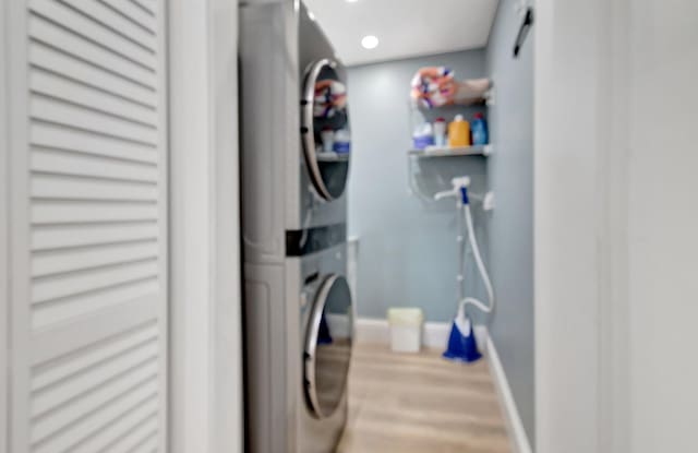 laundry area with wood-type flooring and stacked washer and clothes dryer